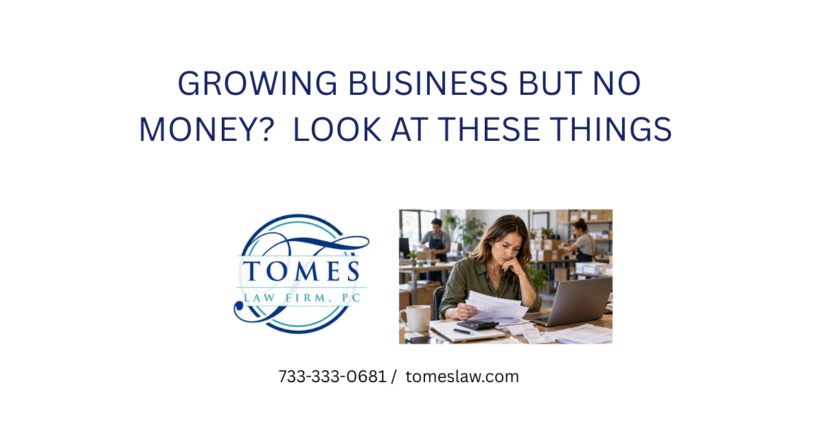 Small business owner reviewing financial paperwork and expenses while employees prepare orders in the background.